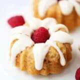 A close up of a glazed mini bundt cake with a fresh raspberry in the middle
