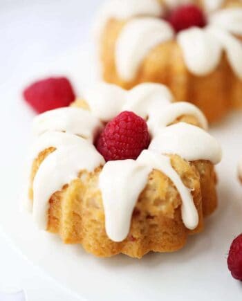 A close up of a glazed mini bundt cake with a fresh raspberry in the middle