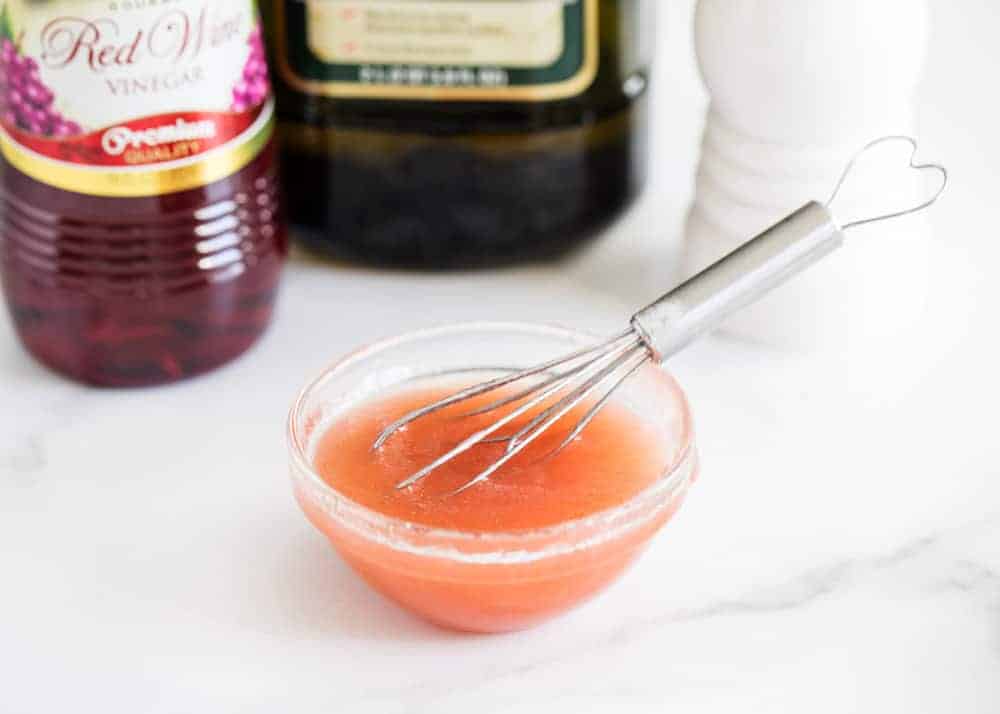 Whisking together red wine vinaigrette in a small bowl.