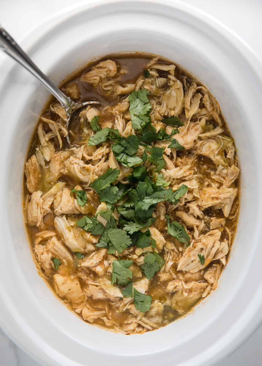 Salsa verde chicken in crock pot with cilantro on top.