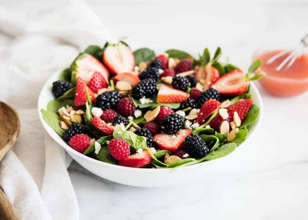 Spinach berry salad in a white bowl.