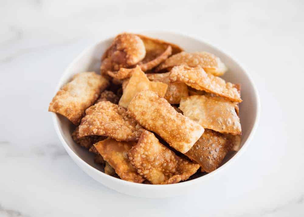 Crispy wonton strips that make the perfect addition to your favorite soups and salads. They can be fried or baked...either way tastes delicious! Wonton strips in a white bowl.