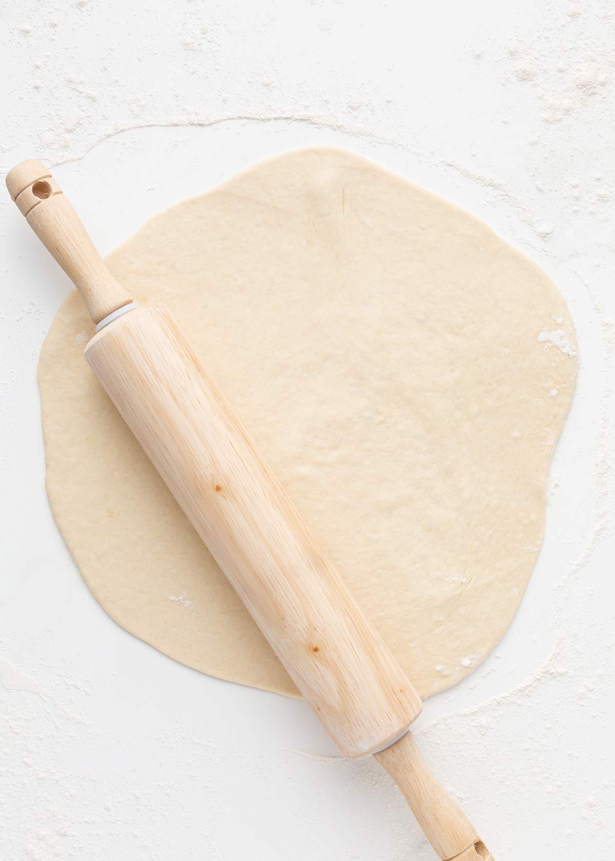 Rolling pizza dough on counter.