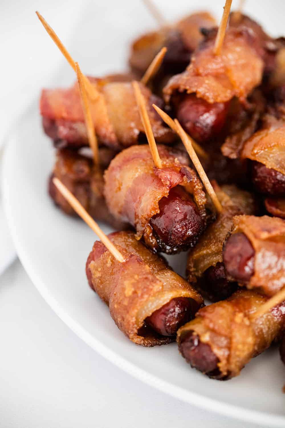 Bacon wrapped smokies on white plate.