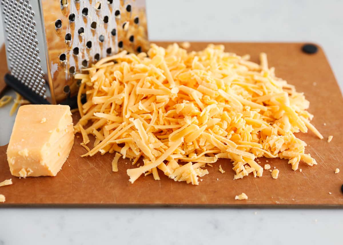 Shredded cheese on a cutting board.