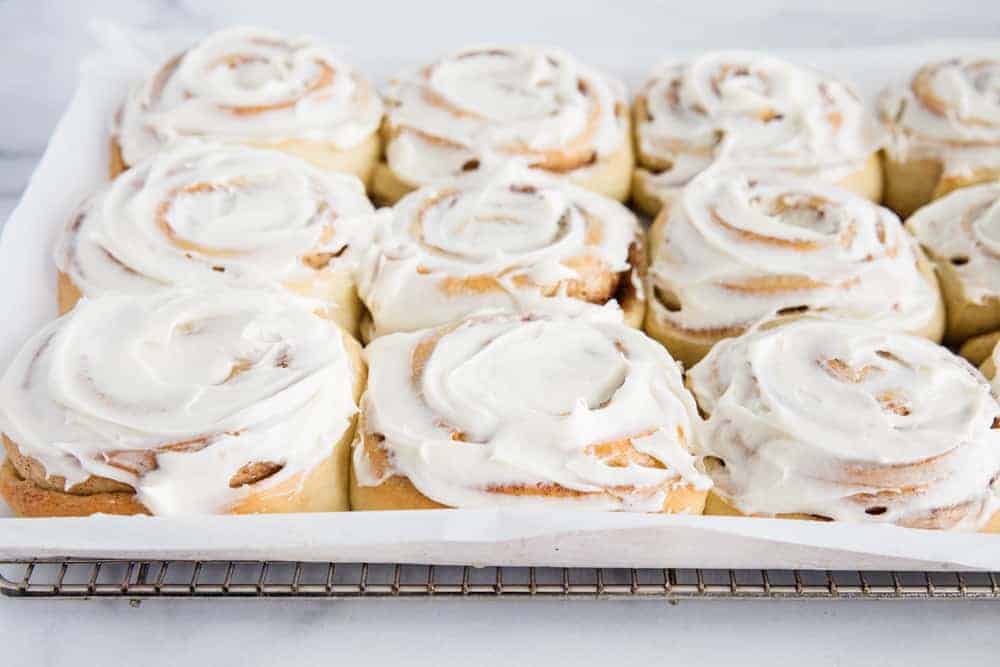 Frosted cinnamon rolls on cooling rack.