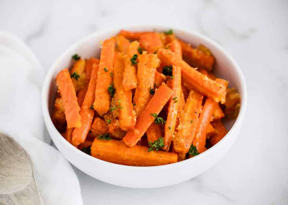 Garlic roasted carrots in white bowl.