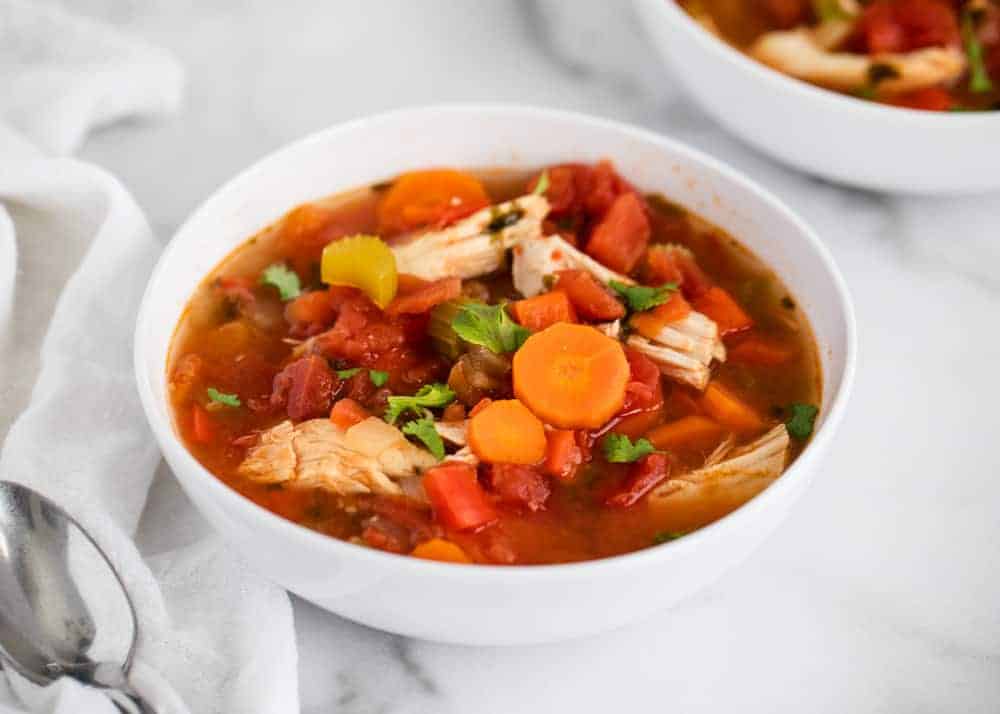 Paleo, gluten-free and Whole30 friendly! An easy crockpot soup recipe that takes just 5 minutes of prep. This Mexican chicken soup is packed with veggies and is healthy and delicious! Mexican chicken soup in white bowl.