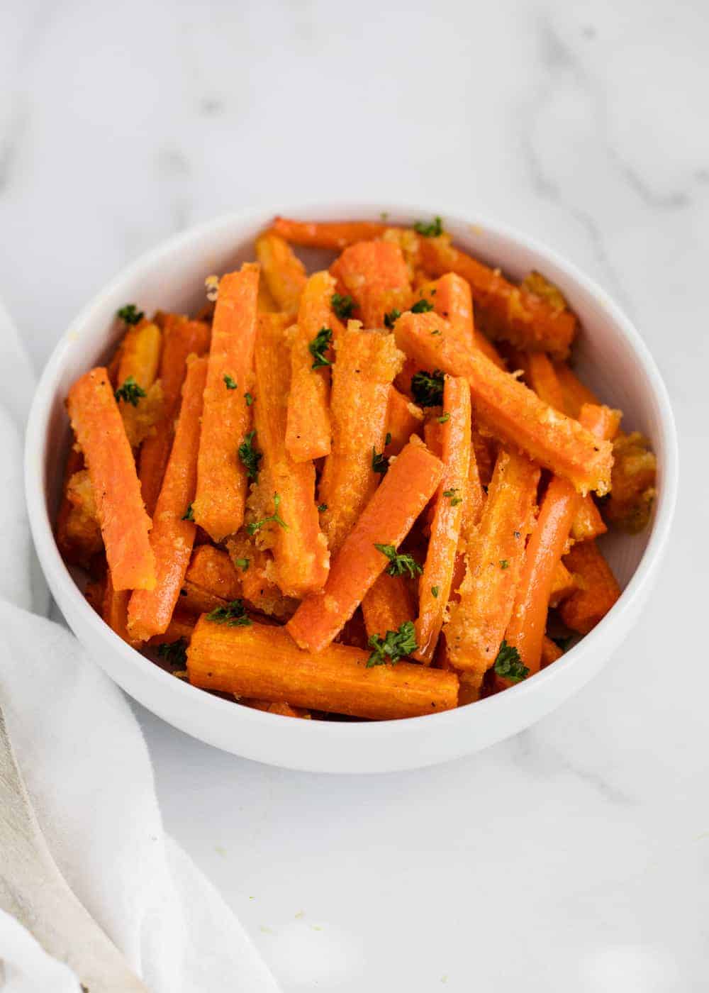 Parmesan roasted carrots in white bowl.