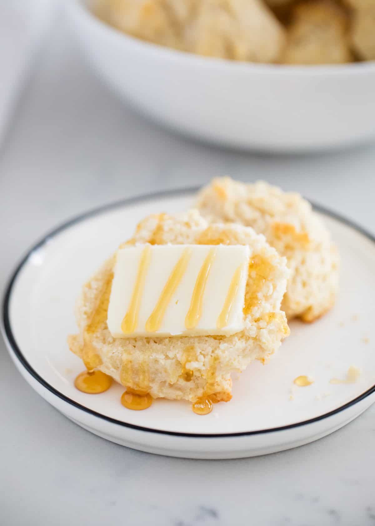 Drop biscuits on a plate split in half with honey and butter.