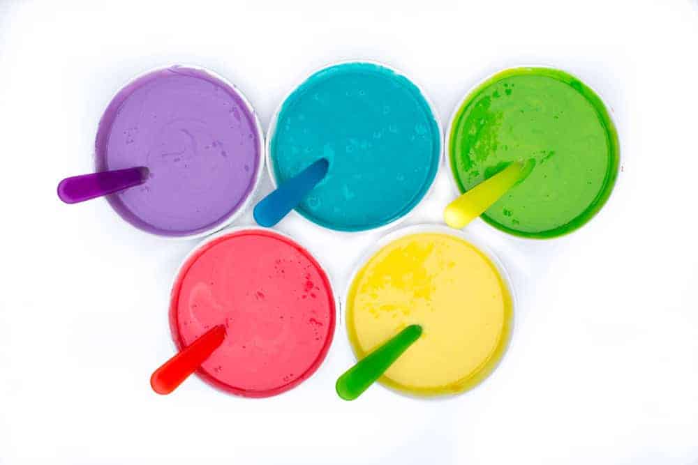 different colored batter in bowls with spoons 