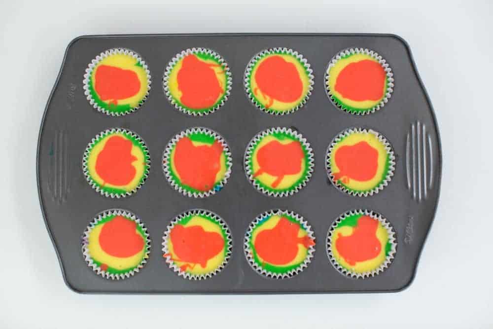 swirled rainbow cupcake batter in cupcake tin 
