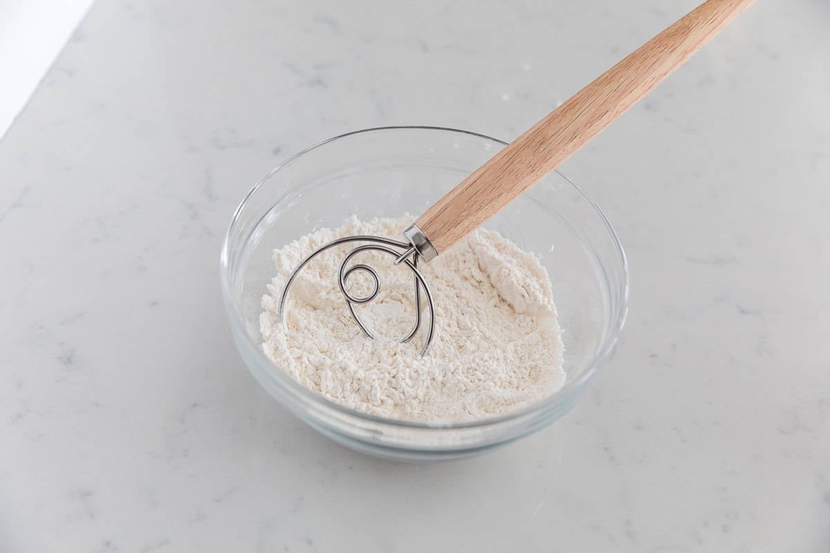 Flour and butter in a bowl with dough whisk.