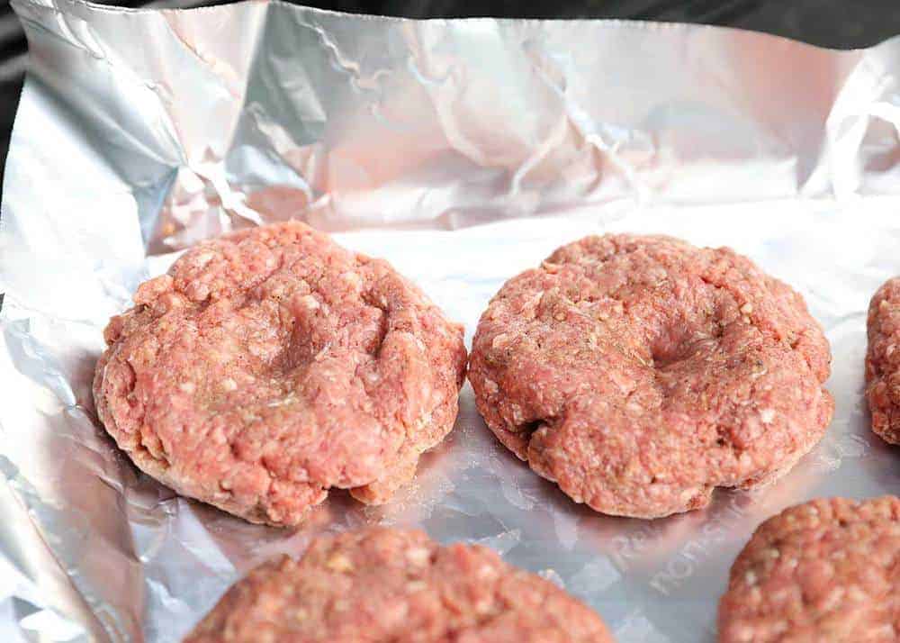 Hamburger patties with a thumbprint well in the middle.