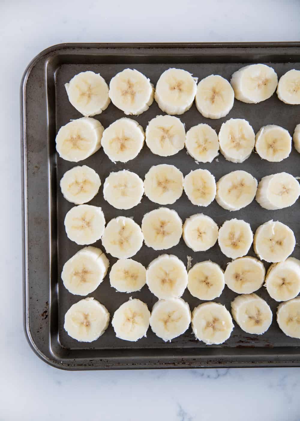 Sliced bananas on baking sheet.