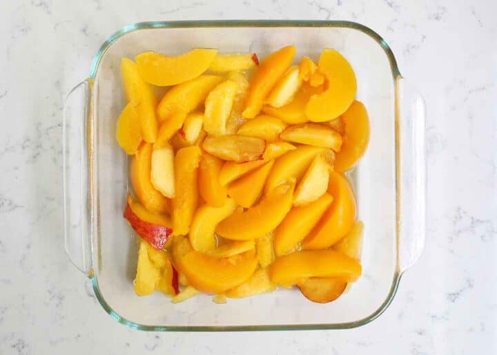 sliced peaches in a glass baking dish 