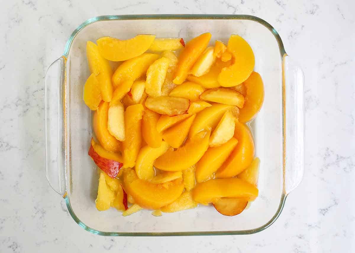 Sliced peaches in a glass baking dish.