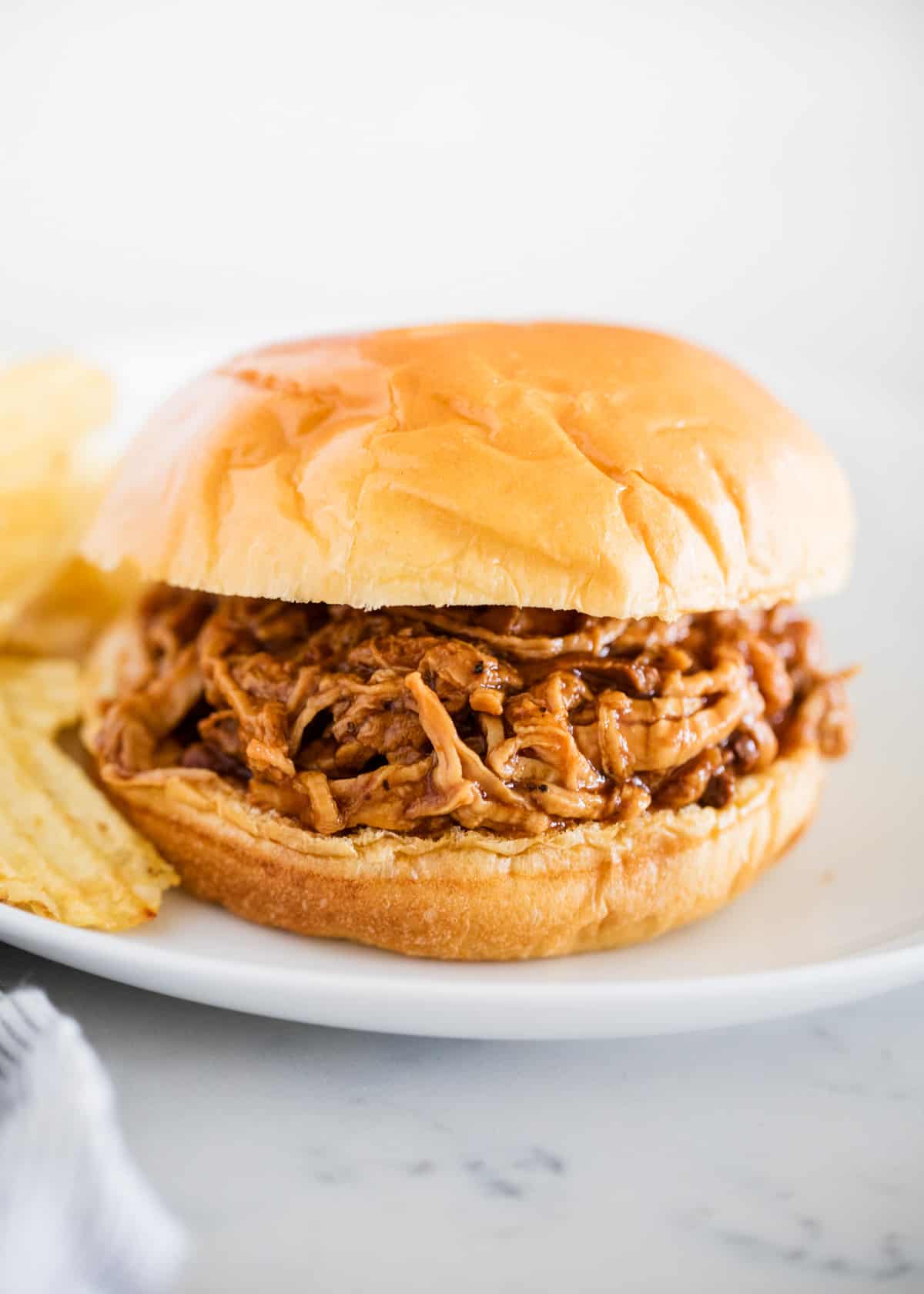 BBQ pulled pork sandwich on white plate.