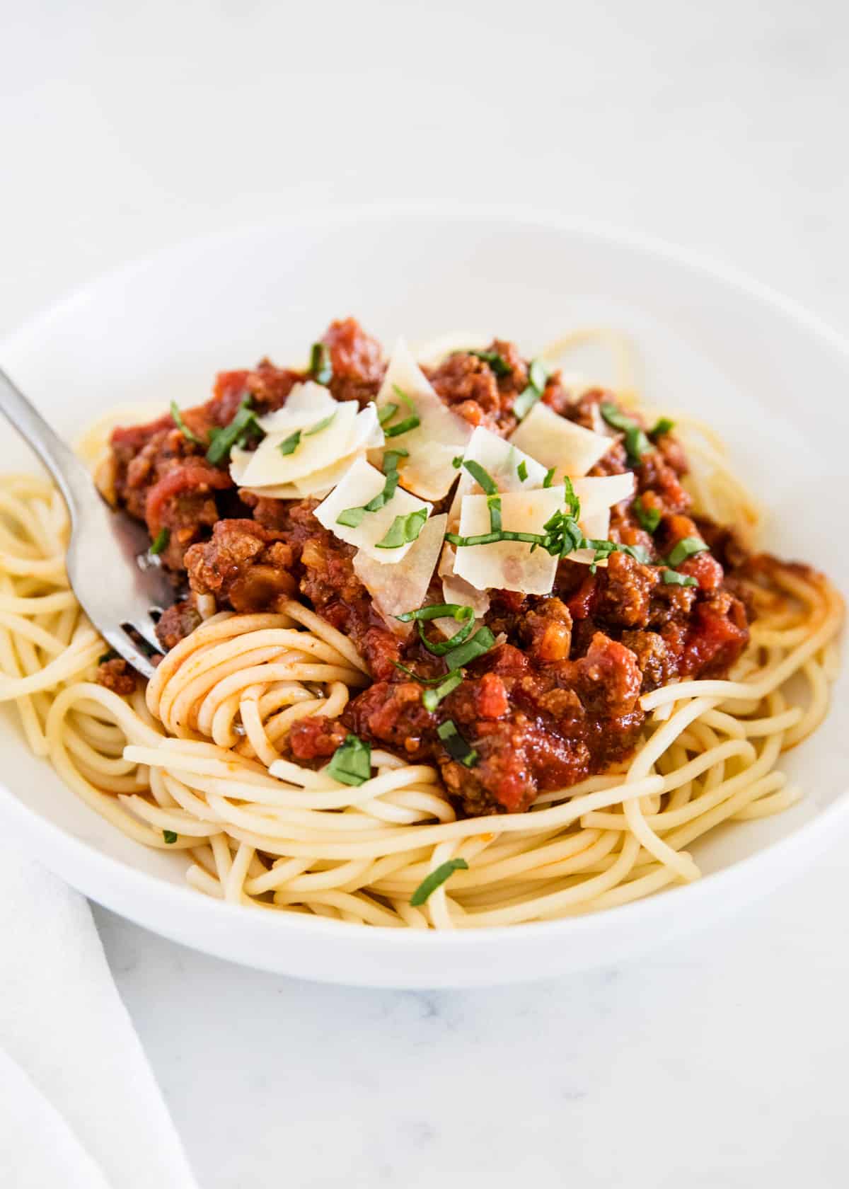 Spaghetti sauce and noodles on white plate.