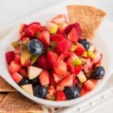 fruit salsa in white bowl with cinnamon chips