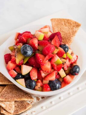 fruit salsa in white bowl with cinnamon chips