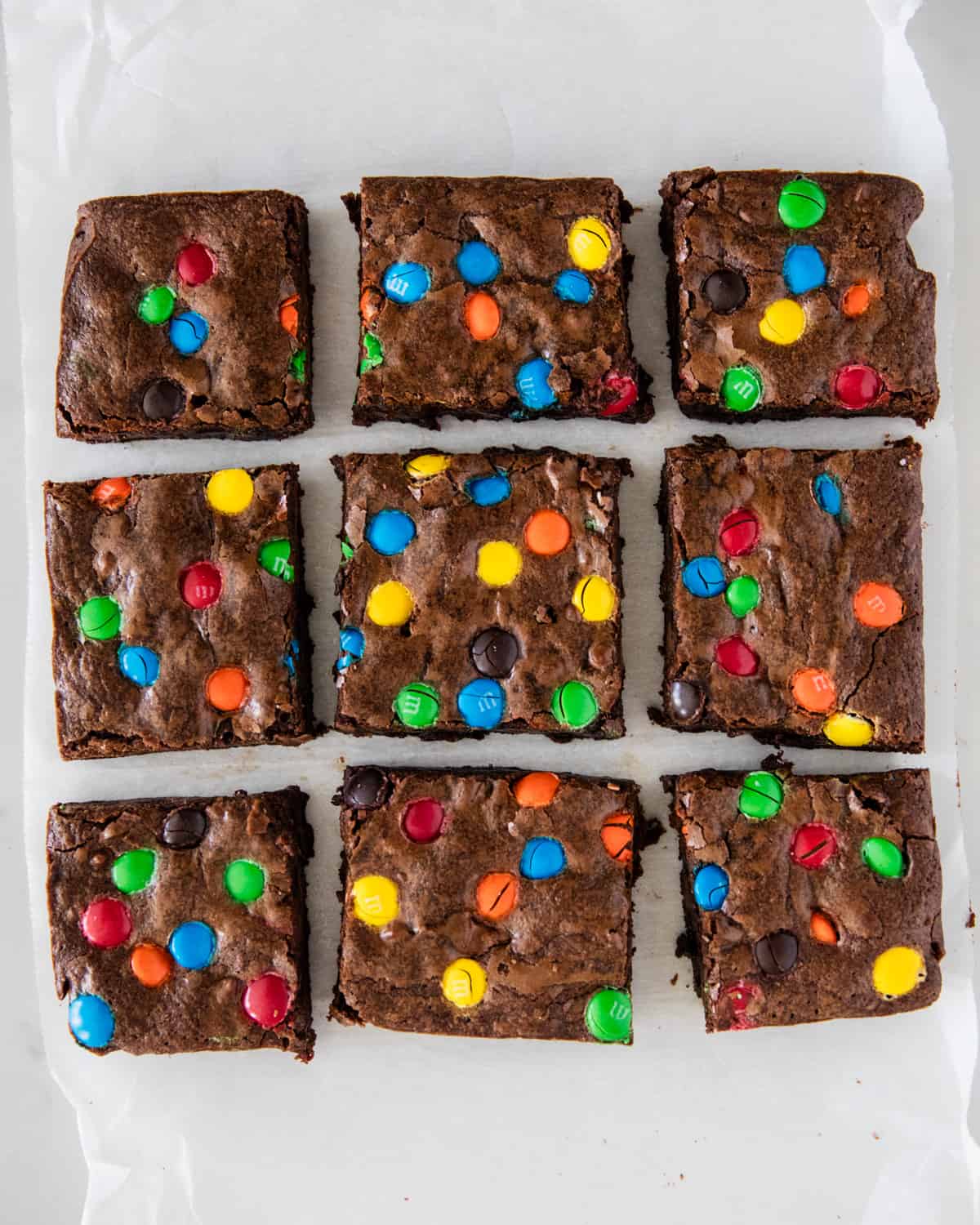 Sliced m&m brownies on parchment paper.