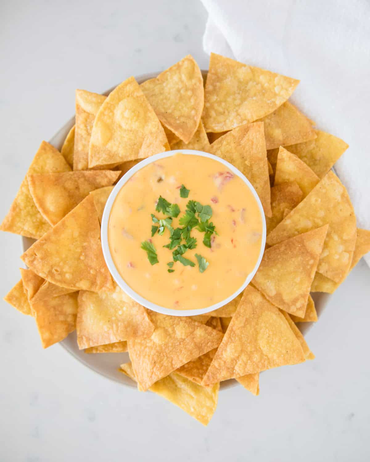 Velveeta queso dip in white bowl with tortilla chips.
