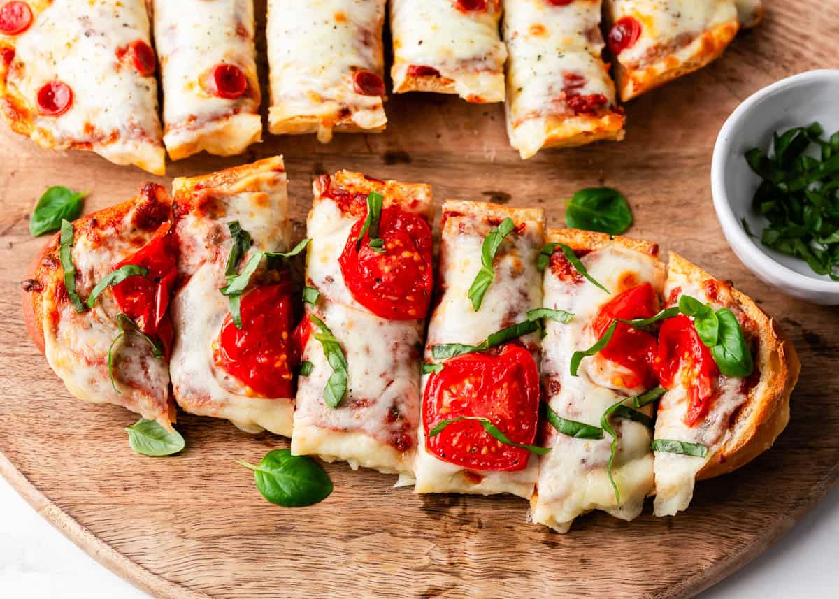 Sliced french bread pizza on cutting board.