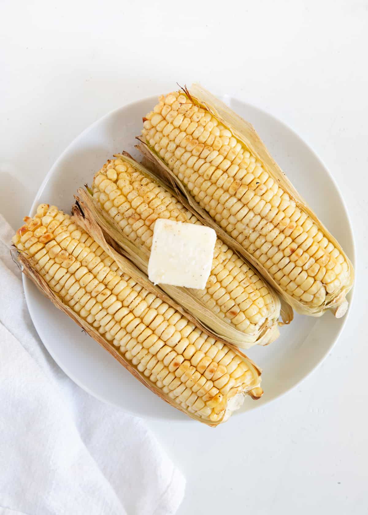 Grilled corn on white plate.