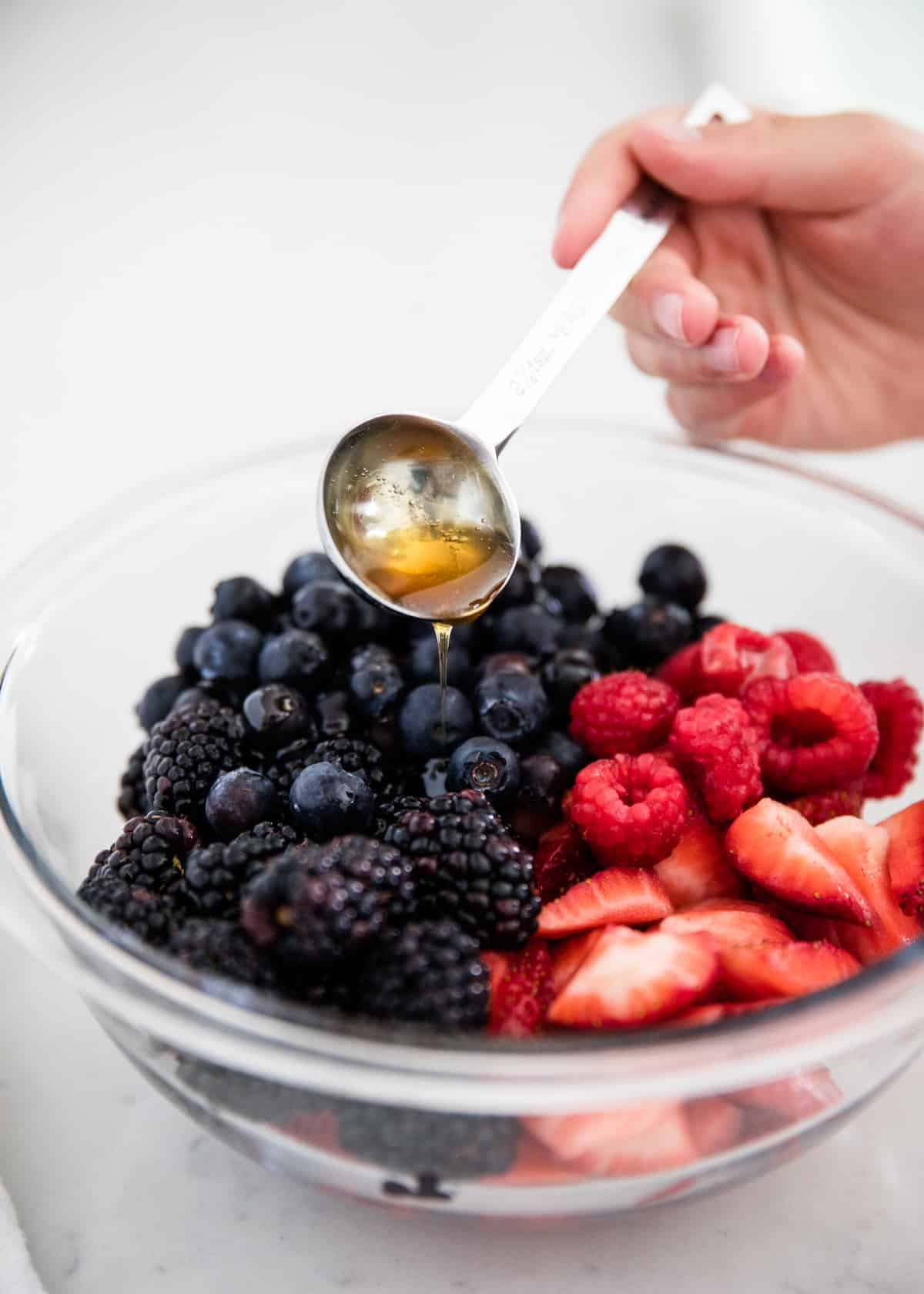 Pouring honey over berries.