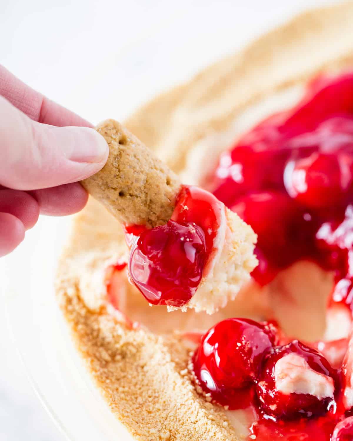 Graham cracker dipped in cherry cheesecake dip.