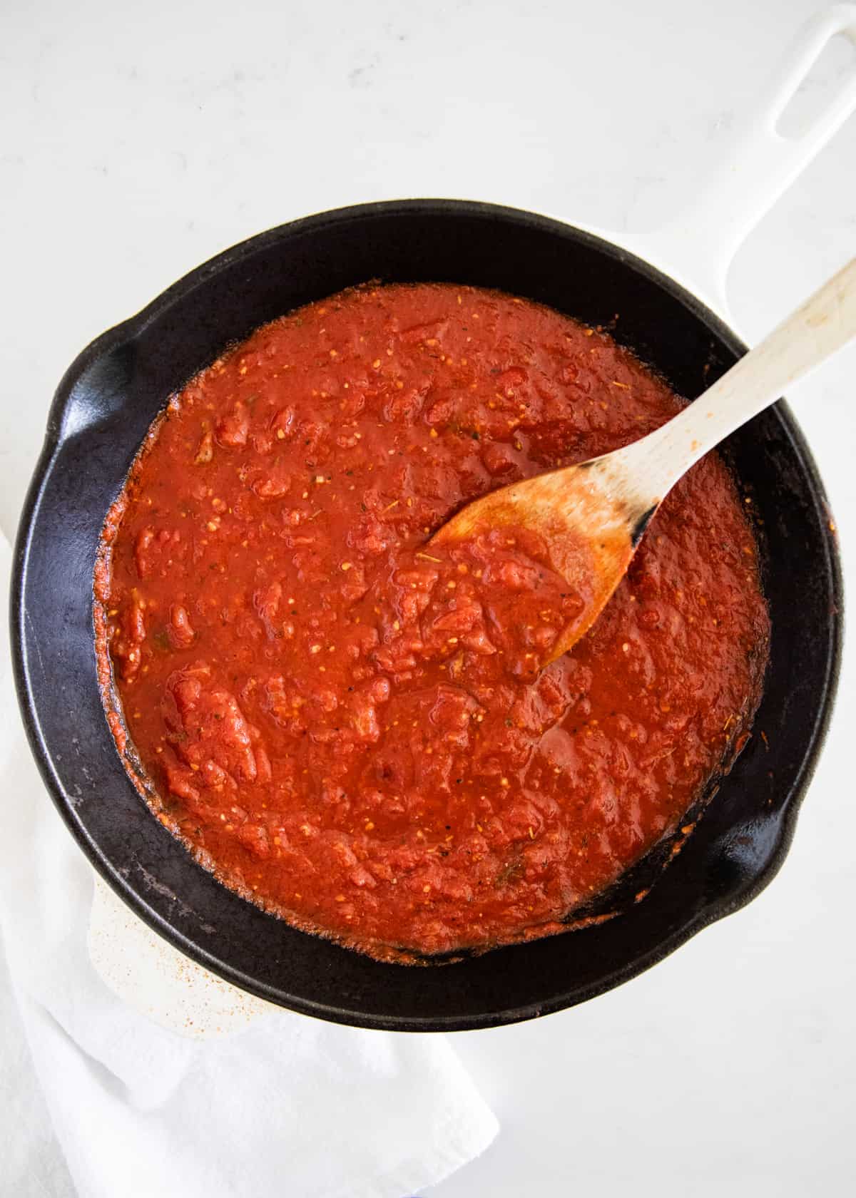 Marinara sauce in a large skillet with wooden spoon.