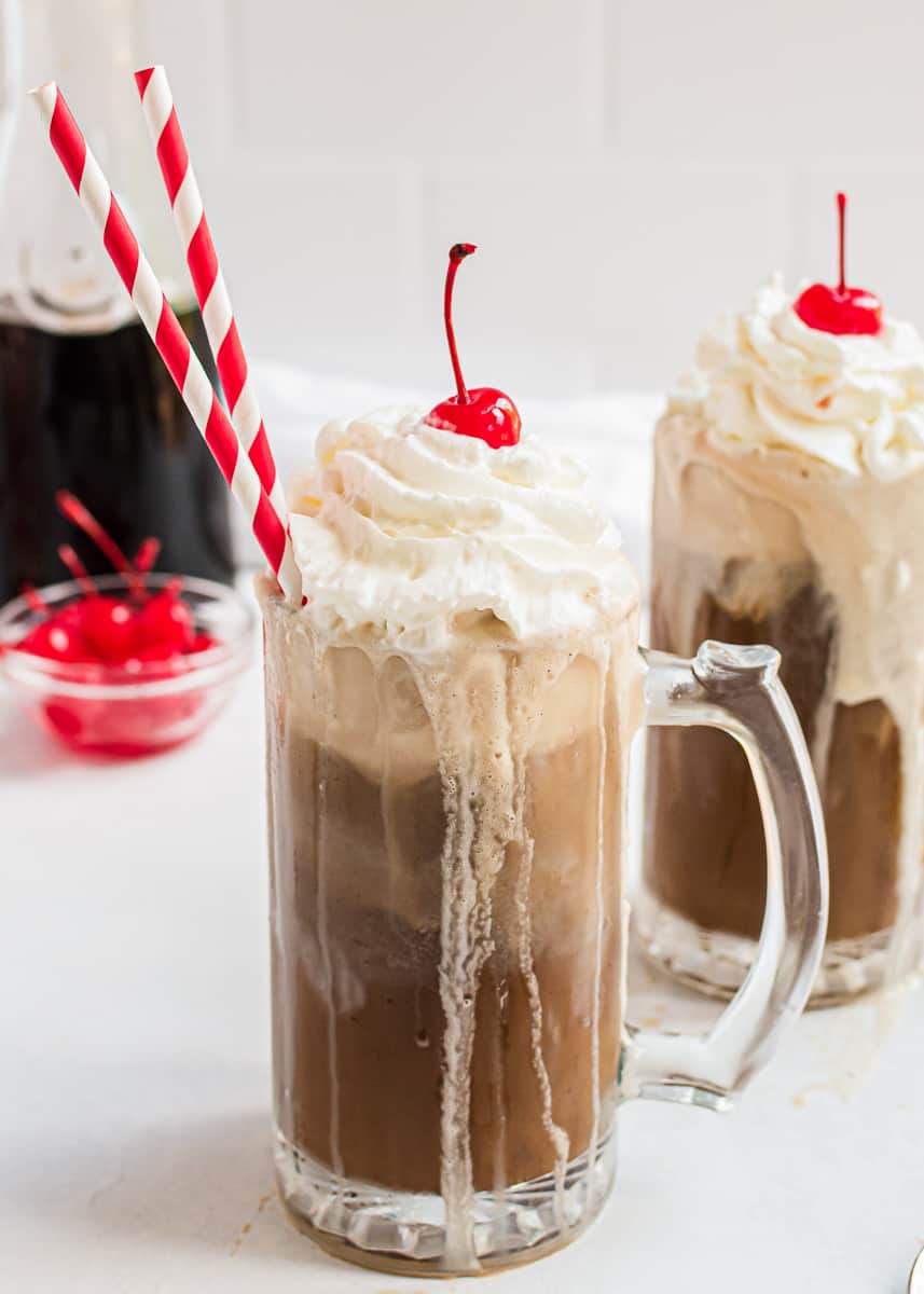 Root beer float with red straw and cherry on top.