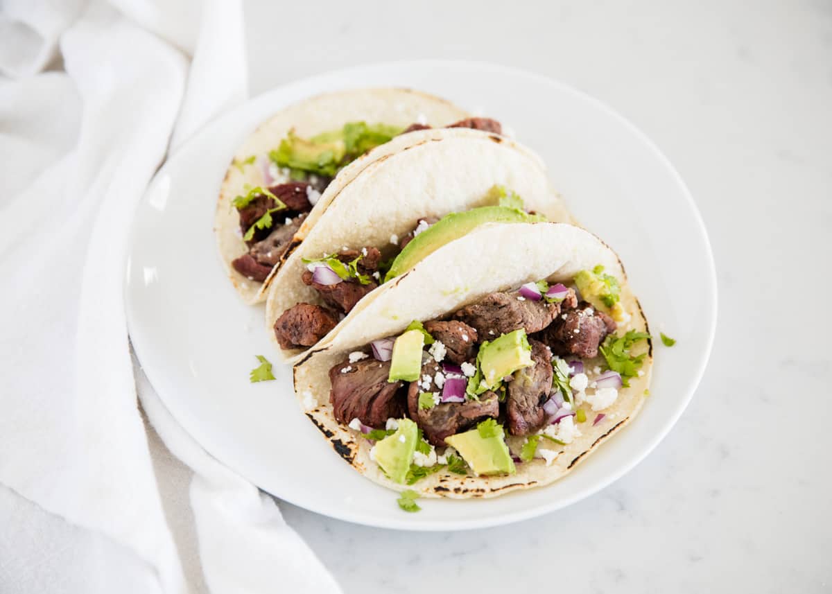 Steak tacos on white plate.