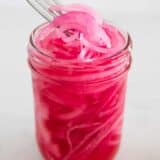 Lifting pickled red onions out of jar with a fork