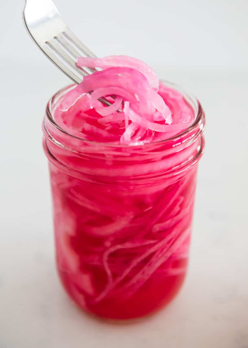 Lifting pickled red onions out of jar with a fork