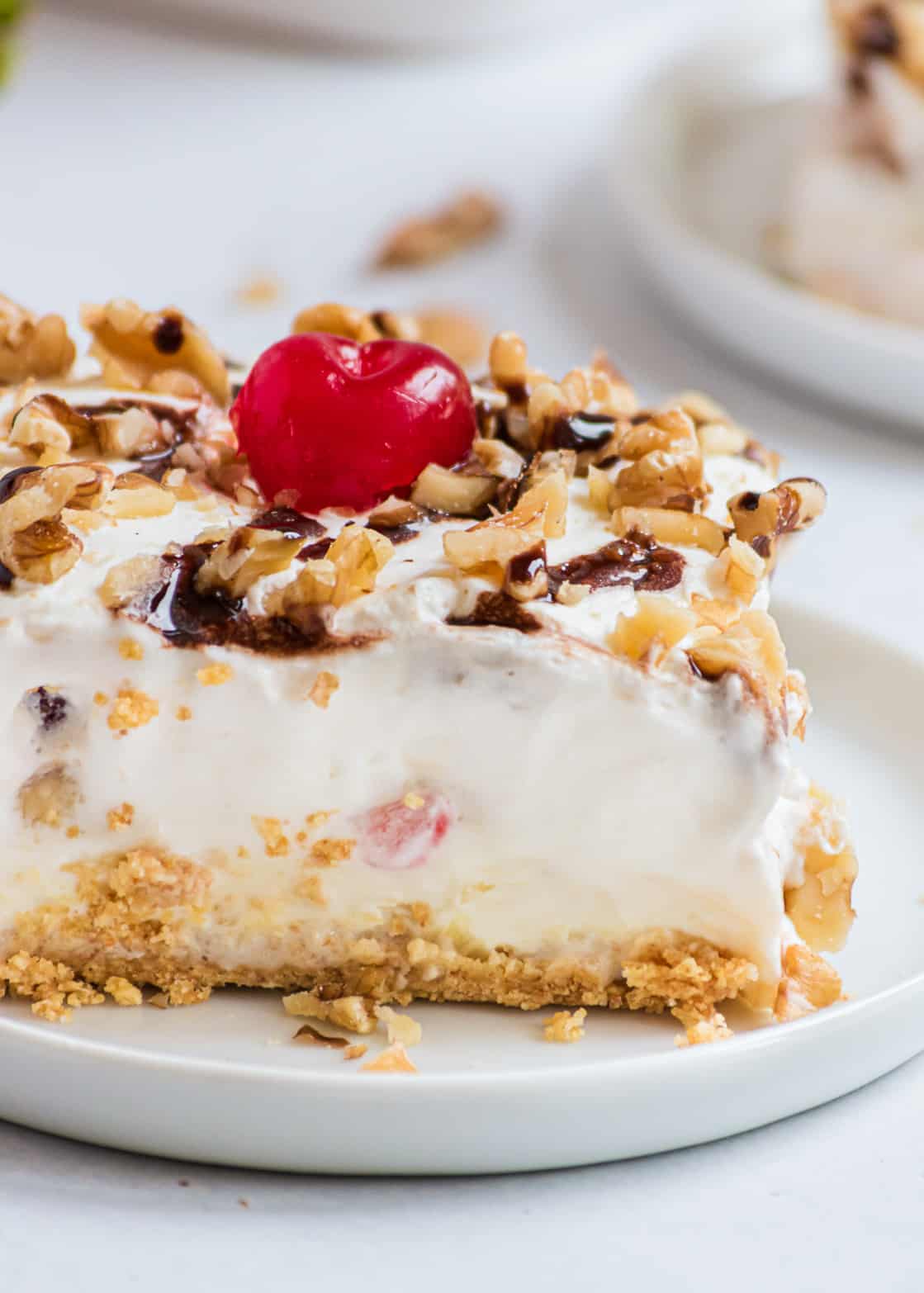 A delicious banana split dessert layered with a graham cracker crust, cream cheese filling, fresh bananas, strawberries and topped with a homemade whipped cream. This easy no-bake dessert is perfect to cool off with this summer! Sliced banana split dessert cake.