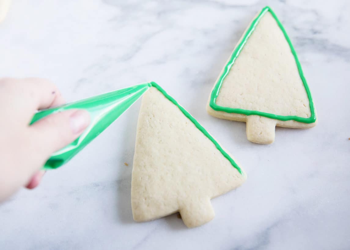 Frosting Christmas tree cookie.