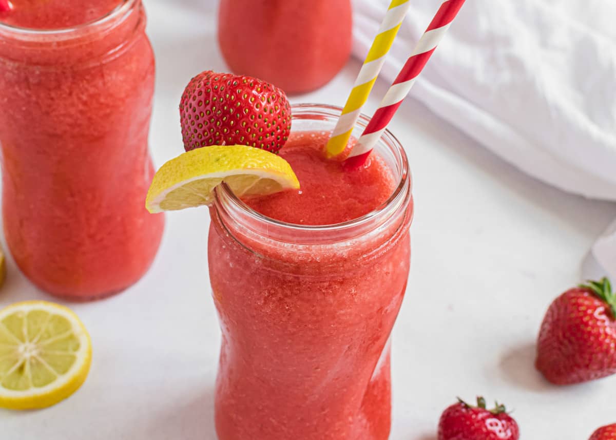 Frozen strawberry lemonade with lemon on cup.