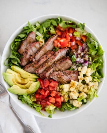 steak salad with avocado in white bowl