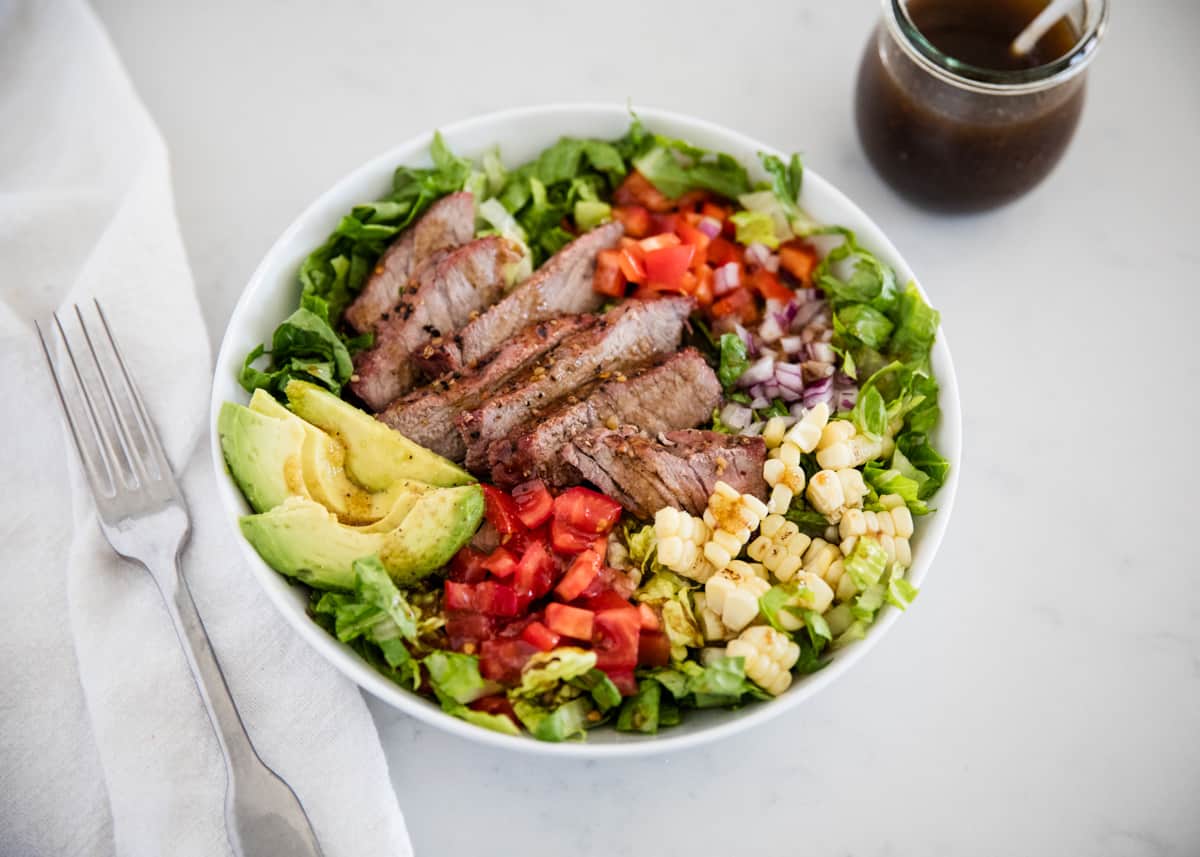 Steak salad in a white bowl.