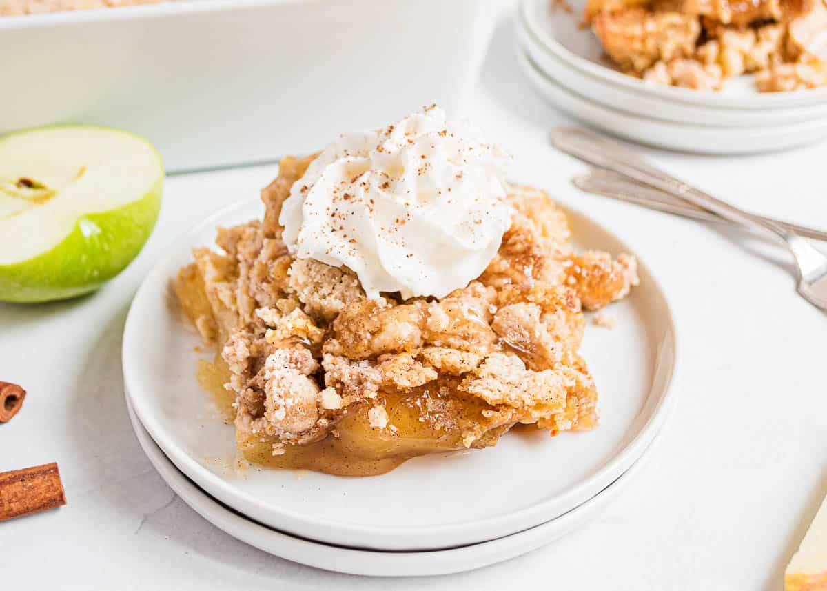 Best apple dump cake with whipped cream on a white plate.