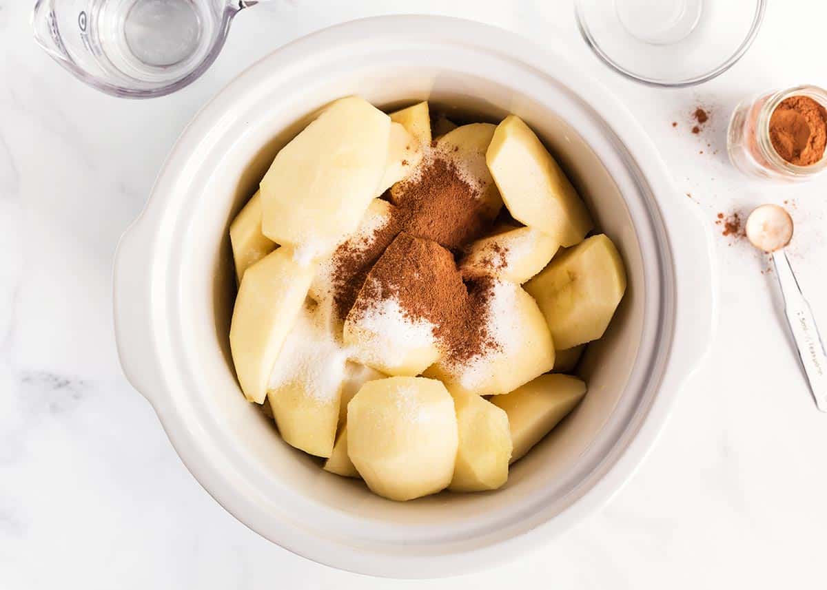 Crockpot applesauce made with only a few ingredients and SO delicious! Once you've made this homemade version, you'll never go back to store bought. So easy and fresh! Applesauce ingredients in white crockpot.