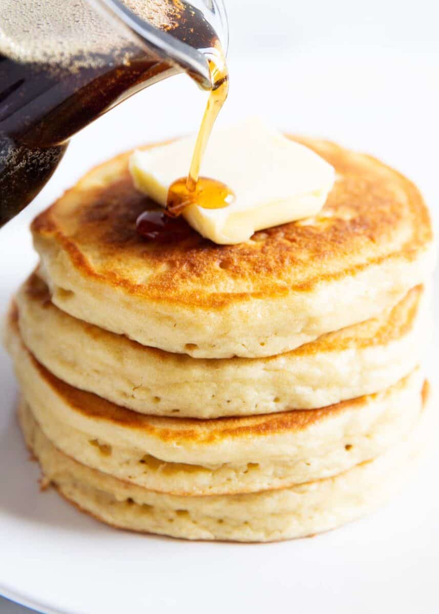 Pouring syrup on a stack of buttermilk pancakes. 