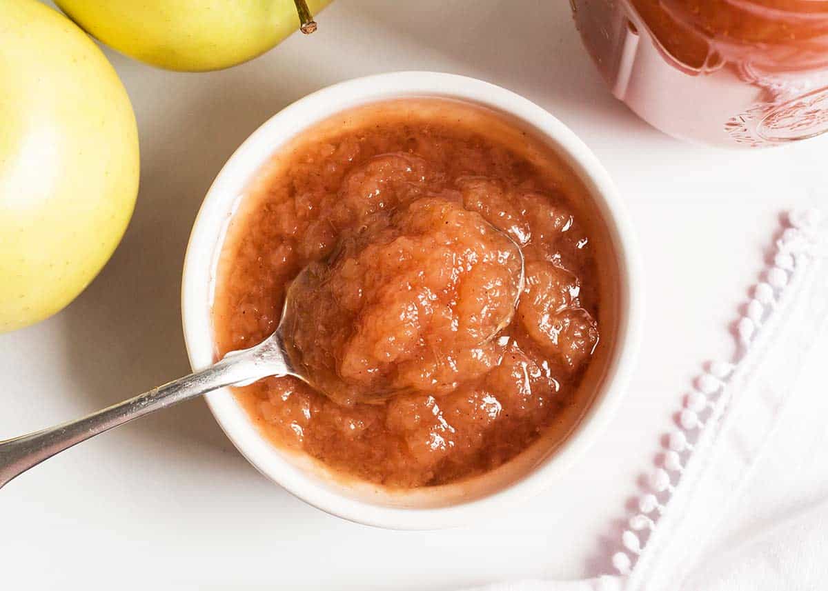 Crockpot applesauce made with only a few ingredients and SO delicious! Once you've made this homemade version, you'll never go back to store-bought. So easy and fresh! Applesauce in a white bowl with a spoon.