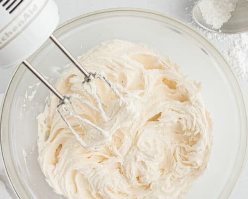 mixing buttercream frosting in glass bowl