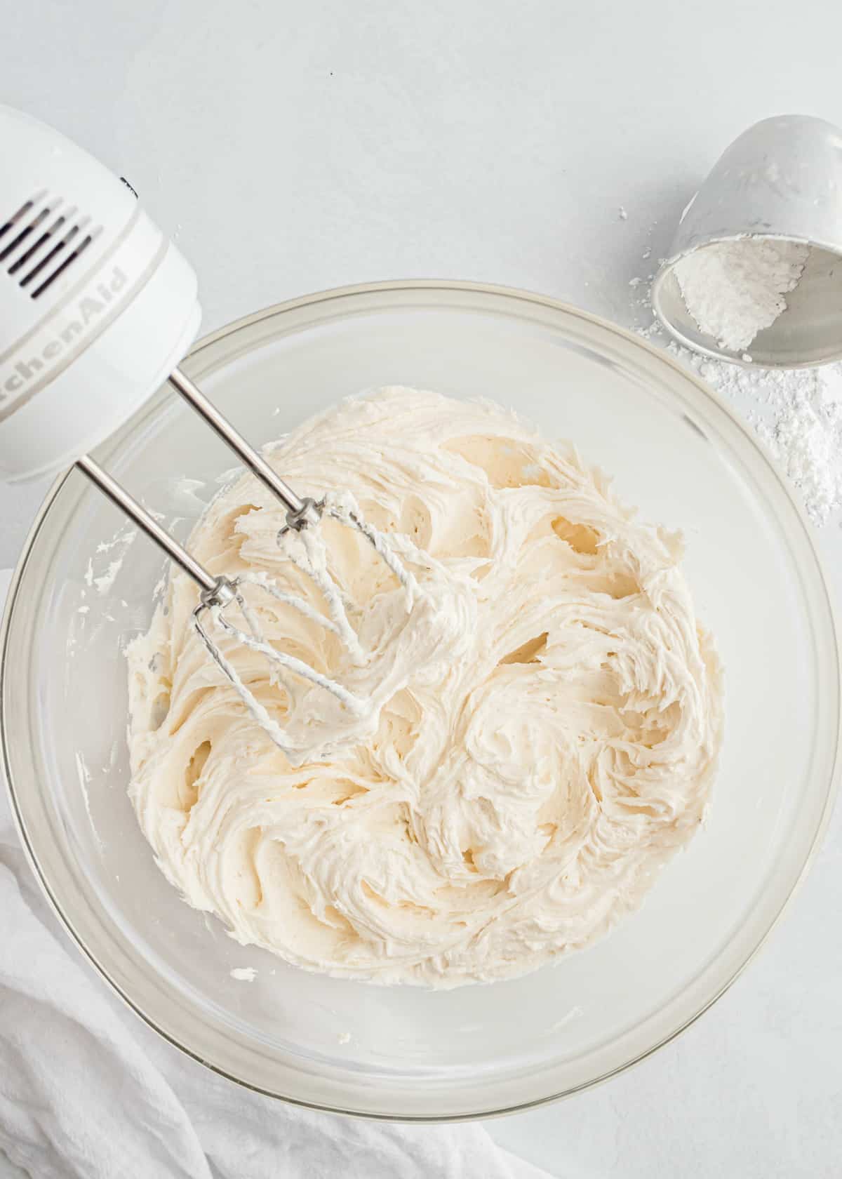 Mixing buttercream frosting in glass bowl.