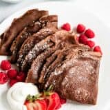 Folded chocolate crepes on a plate.