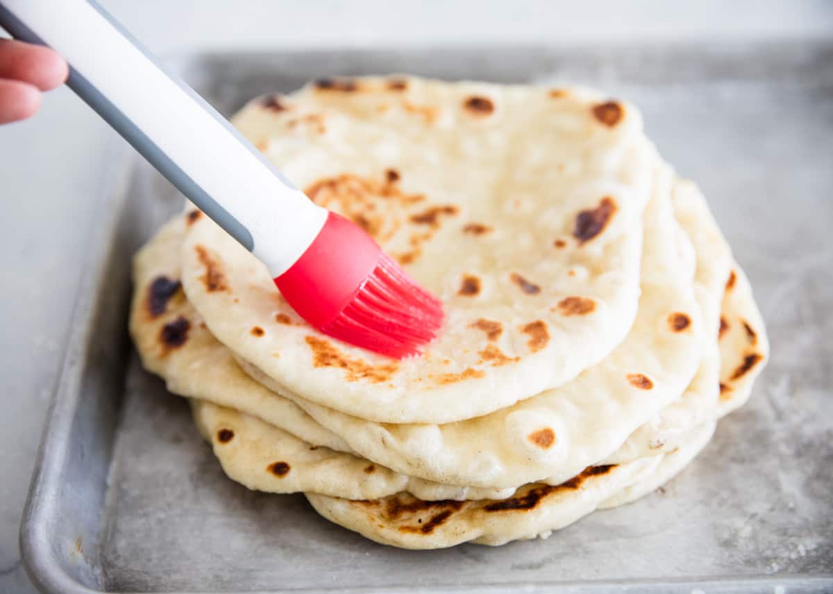 Brushing butter on naan bread.