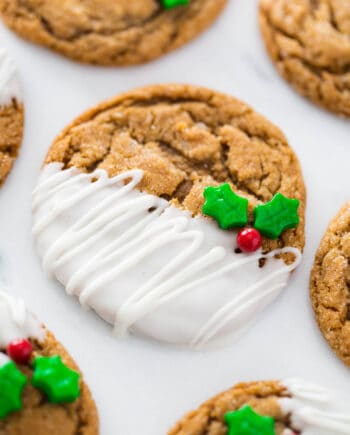 ginger molasses cookie half dipped in white chocolate with a holly berry sprinkle